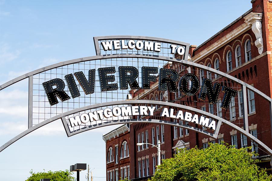 Montgomery, AL Insurance - Metal Sign Reading Welcome to Montgomery, Alabama Riverfront, a Brick Building Behind
