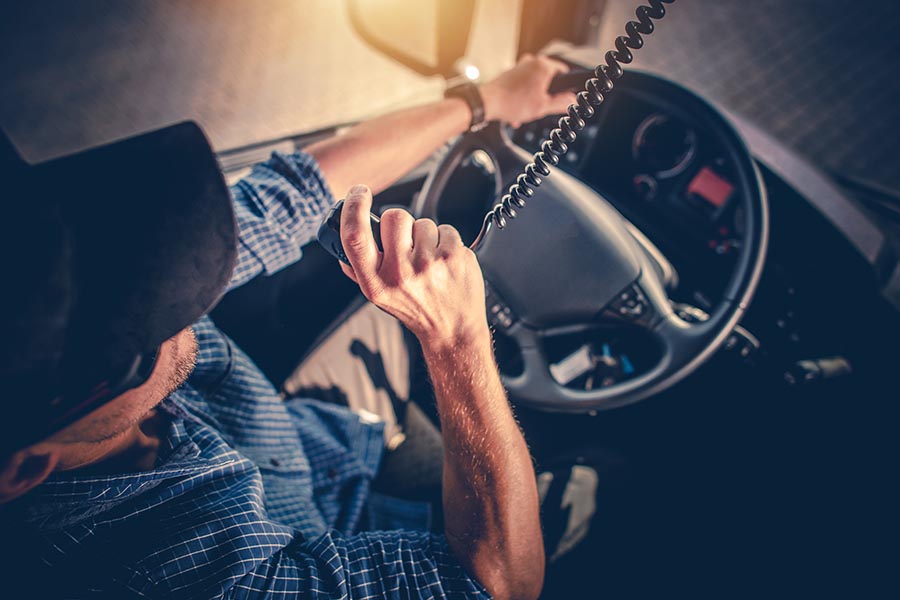 Specialized Business Insurance - Overhead View of a Truck Driver Using a Cab Radio